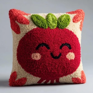 May include: A square throw pillow featuring a textured punch needle design of a smiling red tomato with green leaves on top. The background is cream-colored with red accents in the corners, and the tomato has a black smile and pink cheeks.