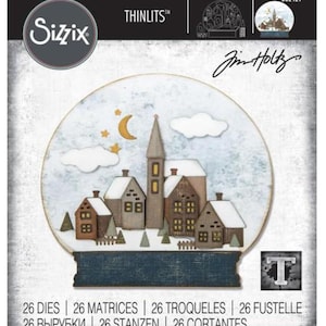 May include: Sizzix Thinlits 662421 Tim Holtz die set featuring 26 metal cutting dies to create a snow globe scene with a village, church, moon, stars, and clouds. The packaging displays a finished winter town graphic with brown houses and white roofs.