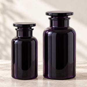Peut inclure: Deux bocaux de style apothicaire en verre translucide violet foncé. Chaque bocal présente un corps cylindrique, un col court avec un rebord prononcé et un couvercle en verre plat et circulaire qui se pose sur le dessus. Les bocaux varient en taille.
