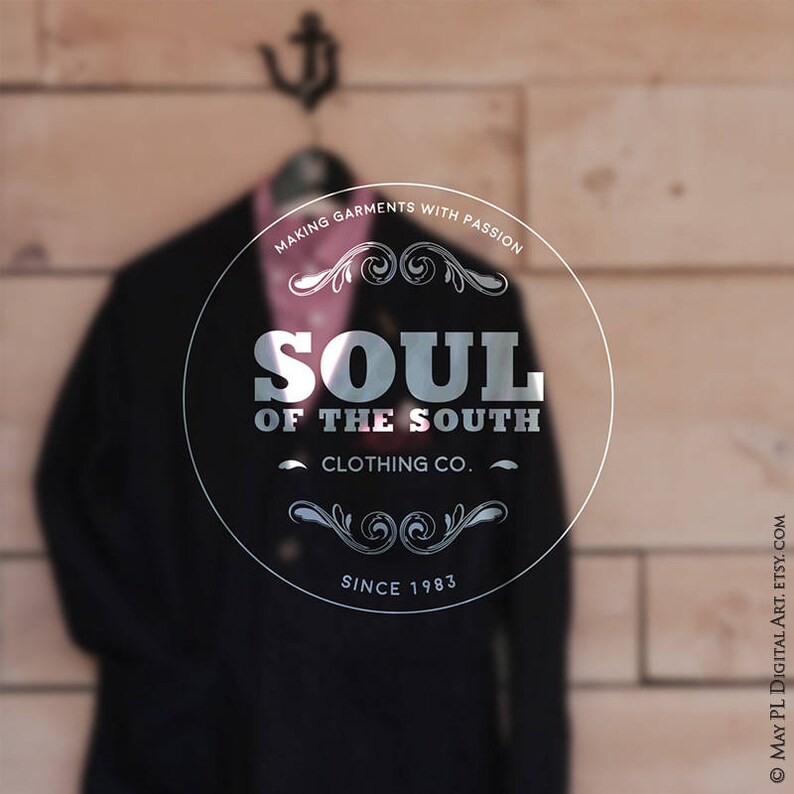 May include: A black blazer and pink shirt hang on a wooden wall. The image features a circular logo with the text "SOUL OF THE SOUTH CLOTHING CO." and "SINCE 1983". The phrase "MAKING GARMENTS WITH PASSION" is also visible.