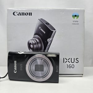Peut inclure: Un appareil photo numérique Canon IXUS 160 noir avec un anneau d'objectif argenté et un zoom optique 8x, placé devant sa boîte d'emballage blanche. La boîte présente le logo Canon, le texte IXUS 160 et une image de l'appareil sur le devant.