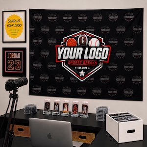 Pode incluir: Um fundo de tecido preto com um padrão repetitivo 'YOUR LOGO' e um gráfico central de escudo com uma bola de basquete, futebol americano e beisebol, rotulado 'YOUR LOGO SPORTS BREAKS EST. 2024'. Inclui duas impressões de parede emolduradas.