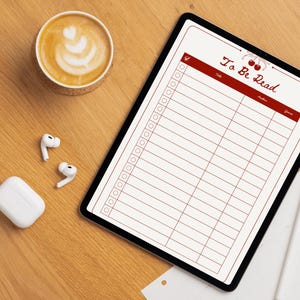 May include: A digital tablet displaying a "To Be Read" list with a cherry design, a cup of coffee with latte art, wireless earbuds, and a charging case on a wooden surface.