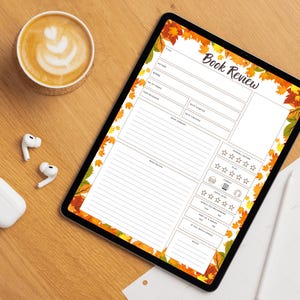 May include: A digital tablet displaying a "Book Review" template with autumn leaf border. A cup of coffee with latte art, wireless earbuds, and a charging case are on a wooden surface.