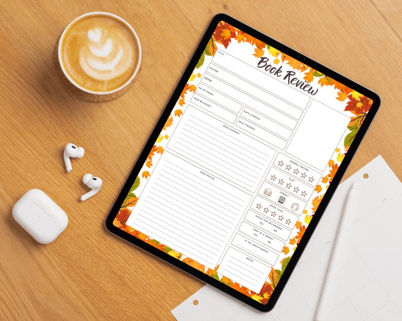May include: A digital tablet displaying a "Book Review" template with autumn leaf border. A cup of coffee with latte art, wireless earbuds, and a charging case are on a wooden surface.