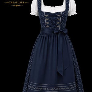 May include: A navy blue dirndl dress featuring a white blouse with short puffed sleeves, a bodice with decorative metal eyelets and ribbon lacing, and a solid navy apron with a bow. The skirt has a floral pattern and a white embroidered hem.