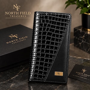 May include: A black vertical wallet featuring a glossy crocodile-embossed texture on one side and a smooth finish on the other. A small gold-toned rectangular plaque with the letters NF is attached to the front. A matching black box is nearby.