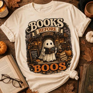 Könnte beinhalten: Ein cremefarbenes T-Shirt mit einer Grafik eines Geistes, der ein Buch mit dem Titel Ghost Stories liest. Das Design zeigt den Text Books Before Boos, ein Schild mit der Aufschrift Spooky Book Club, Bücherstapel, Kürbisse und eine Bibliothek.