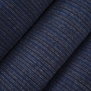 May include: A deep navy blue fabric featuring a repeating pattern of thin, vertical white dashed lines. The textile has a visible woven texture with a consistent, dense arrangement of these light-coloured, broken stripes across the dark surface.