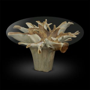 May include: A unique, handcrafted coffee table with a natural wood base and a clear glass top. The base is made from a complex arrangement of light brown and beige wood, creating an organic, sculptural form. The table's dimensions are approximately 48 inches in diameter.