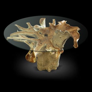 May include: A unique coffee table featuring a natural wood base with an organic, sculptural design. The base supports a clear, oval glass tabletop. The wood has a light brown color with visible grain and texture. The table is set against a black background.