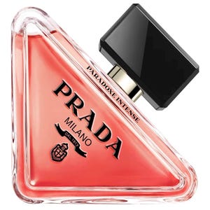 Peut inclure: Un flacon de parfum triangulaire en verre rempli d'un liquide corail. Le flacon présente le logo noir Prada Milano et le texte "PARADOXE INTENSE" imprimés sur le verre. Il est surmonté d'un bouchon rectangulaire noir et d'un col doré.