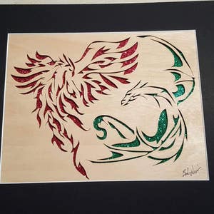 May include: A framed wood carving of two mythical creatures, a red phoenix and a green dragon, intertwined in a dynamic pose. The carving is detailed and intricate, with glitter accents.