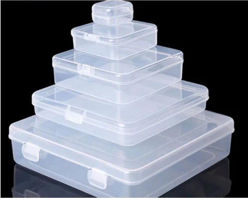 May include: A stack of four clear, rectangular plastic storage boxes with hinged lids and snap closures. The boxes are arranged in descending order of size, with the smallest container at the top and the largest container at the base.