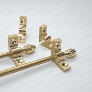 Könnte beinhalten: Eine Sammlung von Messing-Hardware-Komponenten, einschließlich Halterungen und Stangen. Die Hardware hat eine polierte Oberfläche und dekorative Endstücke. Die Komponenten sind für den Einsatz in Möbeln oder dekorativen Anwendungen konzipiert.
