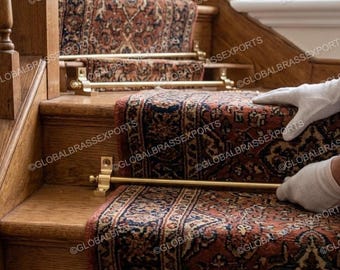 May include: Wooden staircase with a patterned runner rug in shades of red, blue, and cream. Brass stair rods secure the rug to the steps. The image shows a close-up of the stairs.