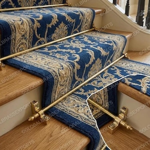 May include: A staircase with wooden steps and a blue and beige patterned carpet runner. Gold-coloured metal rods are installed along the runner's edges, secured by decorative brackets. The carpet has a floral design.