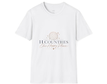 May include: A white short-sleeved t-shirt featuring a graphic on the chest. The design includes a line-art geodesic dome, small stars, and the text 11 COUNTRIES One Happy Place in dark blue and copper tones with a small mouse head icon.