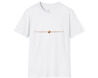 May include: A white short-sleeved t-shirt featuring a horizontal line graphic in brown. The text 28.3744° N is printed on the left, followed by a small brown circle, and 81.5494° W on the right, centered across the chest of the garment.