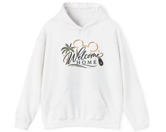 May include: A white long-sleeve hooded sweatshirt featuring a graphic print on the chest. The design includes a gold Mickey Mouse ear outline, a palm tree, and the text "Welcome HOME" in black script and block lettering with a small key fob icon.