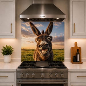 May include: A kitchen backsplash panel featuring a high-resolution photograph of a brown donkey with a wide, toothy grin. The donkey is centered against a backdrop of a grassy field under a sunset sky with soft clouds, positioned behind a stainless steel stove.
