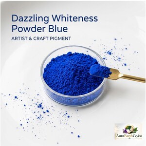 Può includere: Un contenitore in vetro trasparente riempito con pigmento in polvere blu reale per artisti e artigianato, accompagnato da una piccola spatola in metallo dorato. Il testo recita Dazzling Whiteness Powder Blue ARTIST & CRAFT PIGMENT e AuraEarthCeylon.