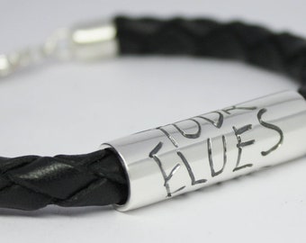 May include: Black leather bracelet with a silver bar engraved with the words "Rock Elves".