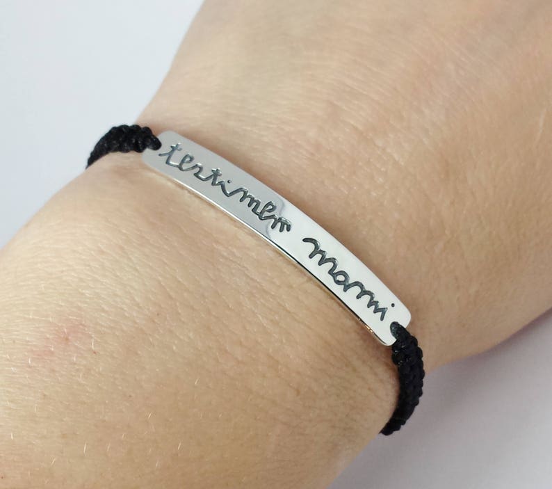 May include: A black cord bracelet with a silver bar charm that reads "I love you Mom".