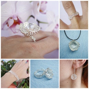 May include: A set of silver jewelry featuring a delicate, intricate design. The set includes a ring, a necklace, a bracelet, and earrings. The jewelry is made of a lightweight, airy material and has a modern, minimalist aesthetic.