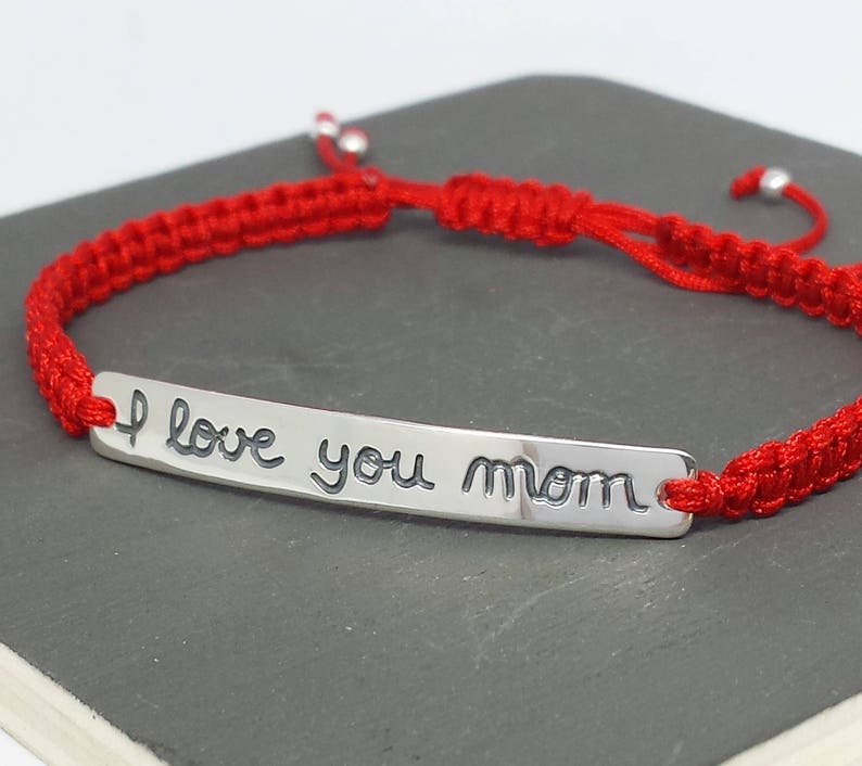May include: Red string bracelet with a silver charm that says "I love you mom".