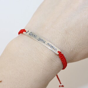 May include: Red string bracelet with a silver charm that says "I love you mom".