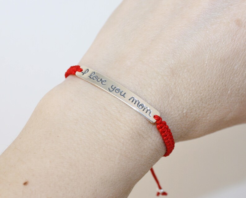 May include: Red string bracelet with a silver charm that says "I love you mom".