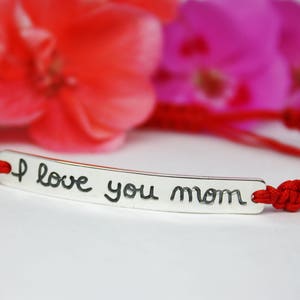 May include: Red string bracelet with a silver charm that says "I love you mom".