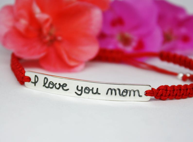 May include: Red string bracelet with a silver charm that says "I love you mom".