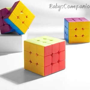 Puede incluir: Tres rompecabezas giratorios 3x3 multicolores con bordes redondeados, que incluyen el texto BabysCompanion en la esquina superior derecha. Los cubos muestran paneles vibrantes amarillos, rojos, azules y morados en una cuadrícula.