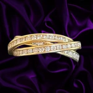 May include: A gold-toned ring featuring a crossover design with two intersecting bands. Each band is embedded with a continuous row of small, clear, round-cut stones that span the entire visible length of the metal setting.