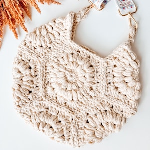 A cream crochet bag on a white background with fall foliage in the corner