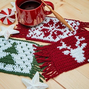 May include: Three crocheted coasters with fringe, featuring a Christmas tree, a snowflake, and a reindeer. The coasters are in green, white, and red.