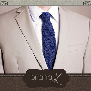 May include: A beige blazer with a blue knitted tie. The tie has a textured pattern. The text "briana K" is visible in the bottom center of the image.