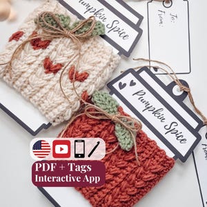 May include: Two crocheted cup sleeves, one cream with small rust-colored hearts and one rust-colored, each featuring a green crocheted leaf and twine bow. They are attached to black and white cardstock tags labeled Pumpkin Spice with twine.
