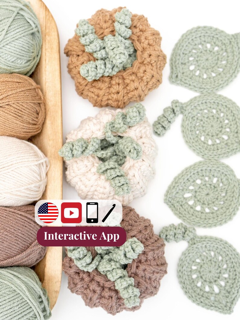 Tan, cream, and brown crochet pumpkins with curly sage vines beside sage leaf coasters and yarn balls on a wooden tray