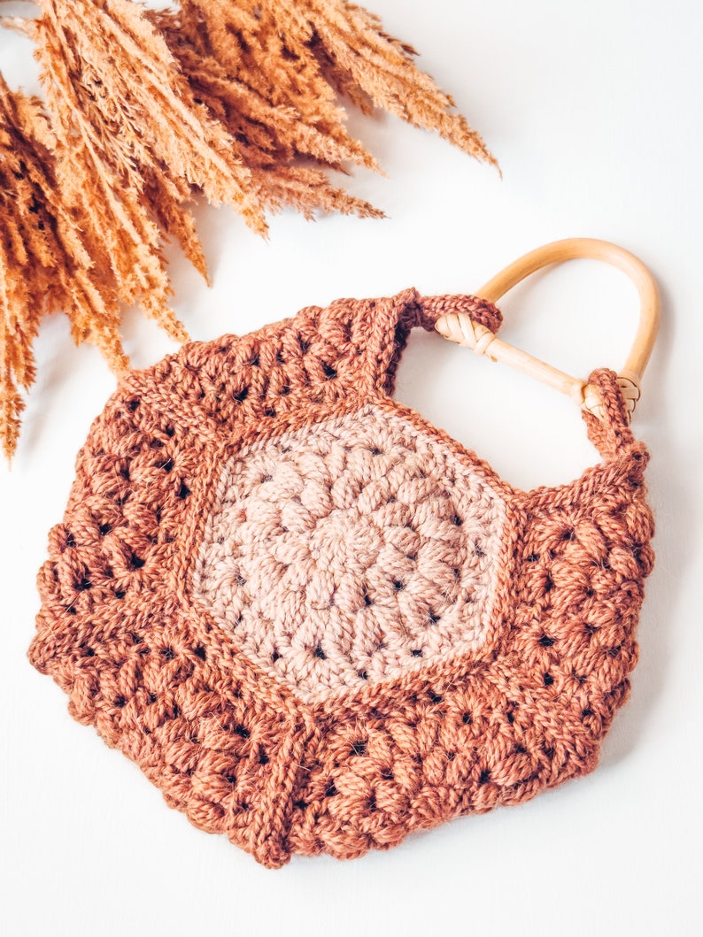A handmade gift featuring a crocheted bag with a wooden handle.