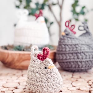 Small oatmeal crochet chicken with braided texture on wood slices, with white and gray hens blurred behind