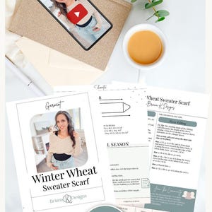 Flat lay with a phone displaying a video thumbnail, a cup of coffee, plant, and printed crochet pattern sheets titled "Winter Wheat Sweater Scarf." Perfect for those seeking unique handmade gifts to pair with vintage clothes.
