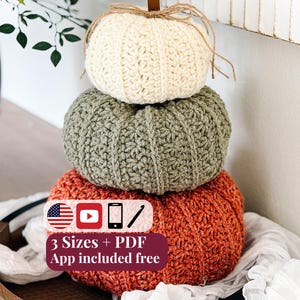 May include: A stack of three crocheted pumpkins in cream, sage green, and burnt orange, topped with a brown leather stem and twine bow. A maroon graphic overlay displays the text 3 Sizes + PDF App included free with icons of a US flag, YouTube, phone, and crochet hook.