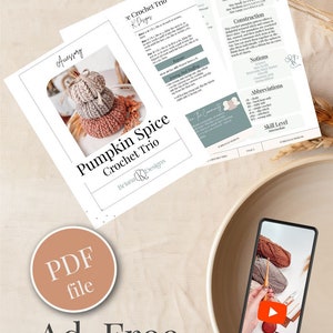 A crochet pattern for a Pumpkin Spice Crochet Trio is displayed on a table alongside a bowl and a phone showing a crochet video. The text highlights an ad-free, PDF file download, making it perfect for crafting handmade gifts.