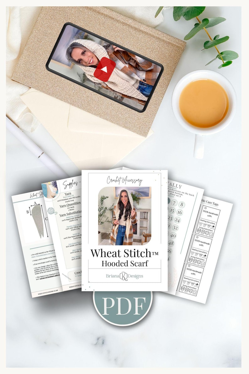 May include: A selection of crochet accessory patterns, including a "Wheat Stitch Hooded Scarf" design, with care tags and yarn information. A video on a phone shows the scarf. A cup of tea and a pen are also visible.