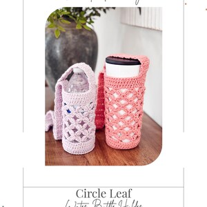 Puede incluir: Dos portabotellas de ganchillo con patr&oacute;n de hojas circulares y correas largas. Uno es de color lavanda claro y contiene una botella de pl&aacute;stico, el otro es rosa coral y sostiene un vaso blanco con tapa negra. Texto: Crochet Accessory, Circle Leaf Water Bottle Holder, Briana K Designs.