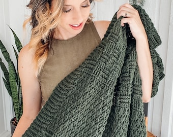 May include: A dark forest green knitted blanket featuring a prominent basketweave texture. The textile is crafted with a thick yarn, creating a dense and uniform pattern of interlocking squares that run throughout the entire surface of the fabric.