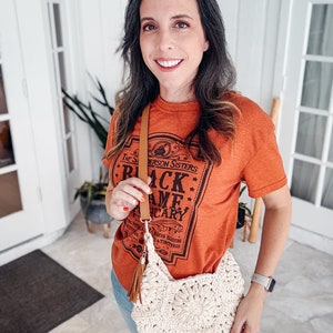 A woman wearing vintage clothes and holding a crocheted purse.